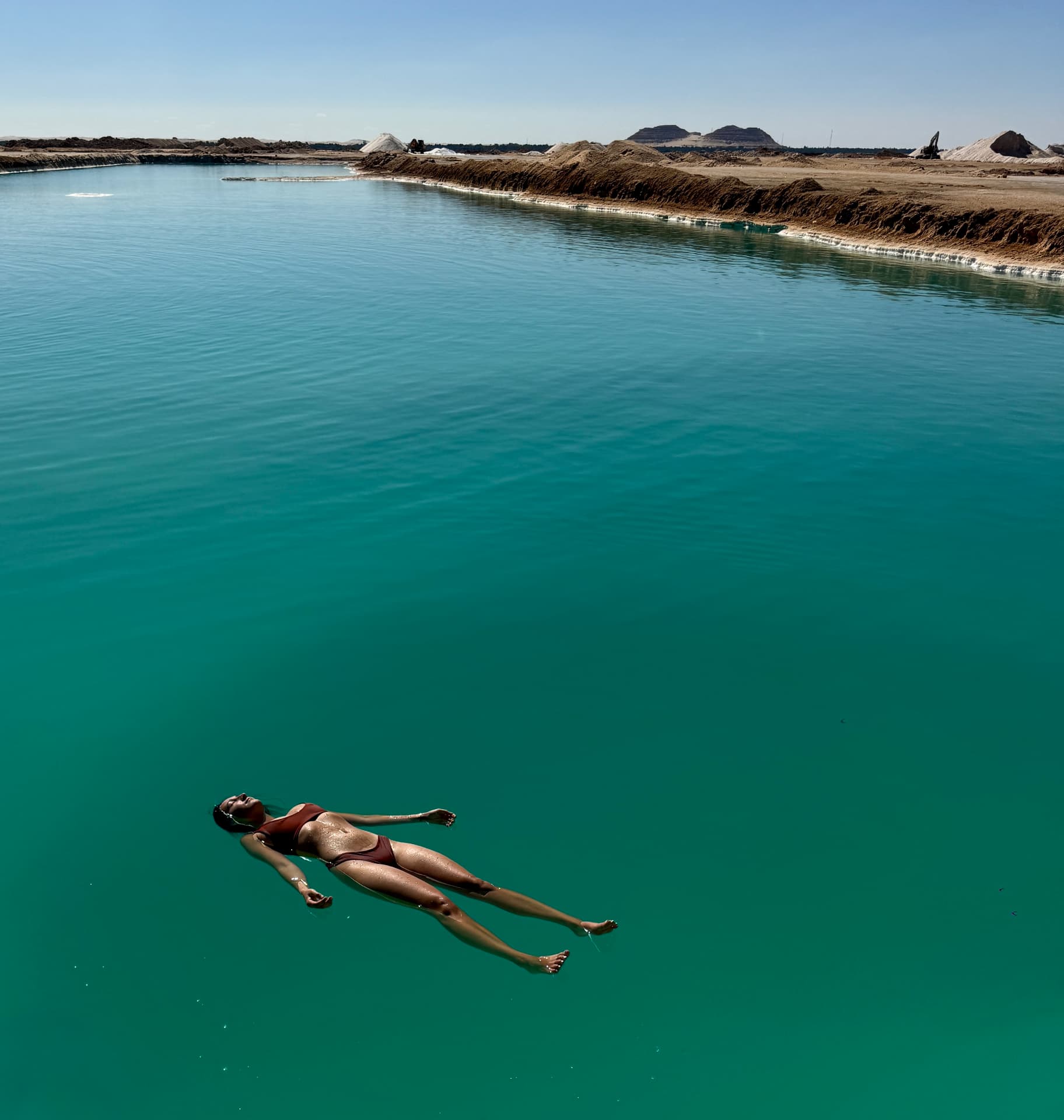People floating in a turquoise salt lake in Siwa Oasis